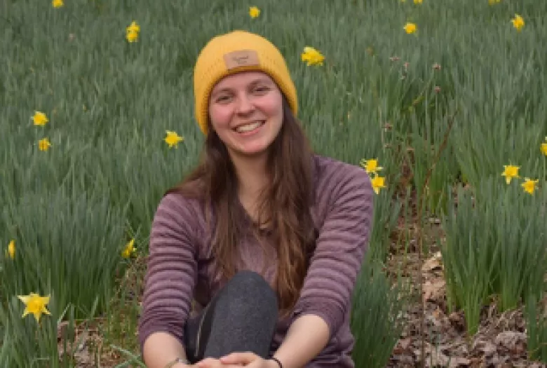 Smiling woman sitting in a field of daffodils